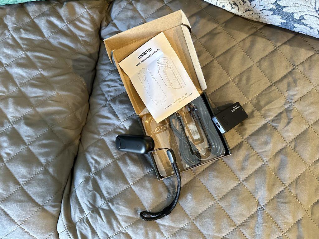 Contents of UNIBITRI Remote Page Turner package on a bed