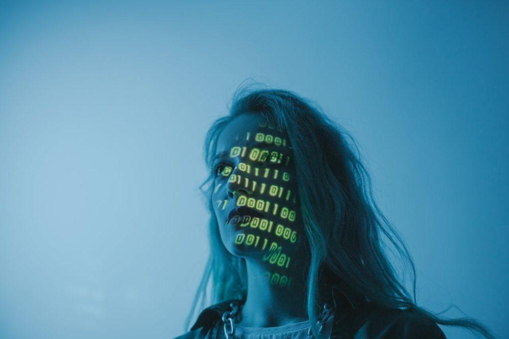a woman looking outward with binary code projected on her face